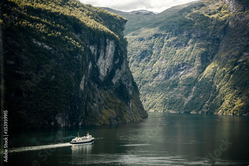 Panoramic view of Geiranger Fjord with floating touristic ferry in the cloudy summer day. Trip to Norway