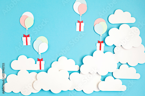 Papercut balloons and Gift Box floating in blue sky with clouds. Happy Bithday  Merry Christmas festive poster. Greeting card with paper craft