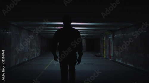 a man walks in the evening lighted underpass photo