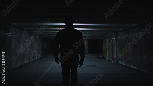 a man walks in the evening lighted underpass