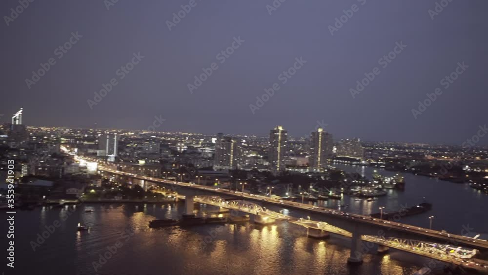 Panning shot of bridge over river in modern city against sky at night - Bangkok, Thailand Panning shot of bridge over river in modern city against sky at night - Bangkok, Thailand