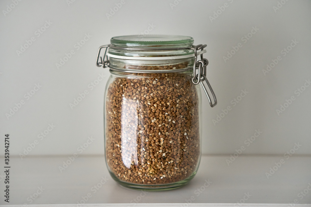 Glass jars with a lid for food on a white shelf. Storage in the kitchen. Containers with bulk products. Transparent container. Glass jars with a lid for food on a white shelf. Storage in the kitchen. Containers with bulk products. Transparent container.