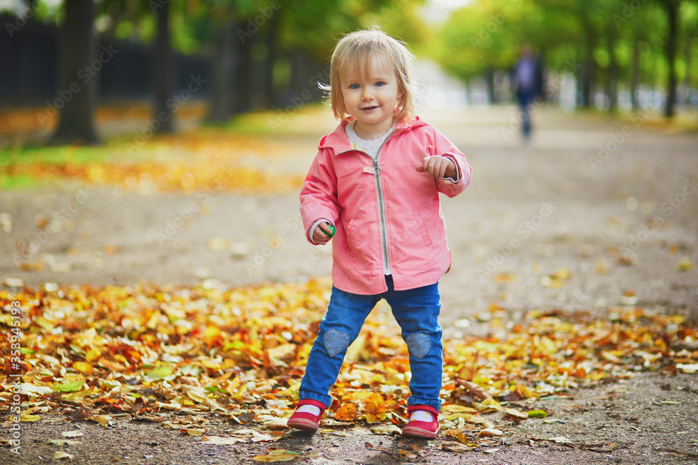 Adorable cheerful toddler girl running in Tuileries garden in Paris Adorable cheerful toddler girl running in Tuileries garden in Paris