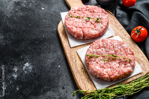 Raw chicken patty, ground meat cutlets on a chopping Board. Organic mince. Black background. Top view. Copy space