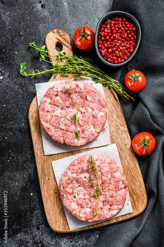 Raw pork cutlets, ground meat patty on a cutting Board. Organic mince. Black background. Top view
