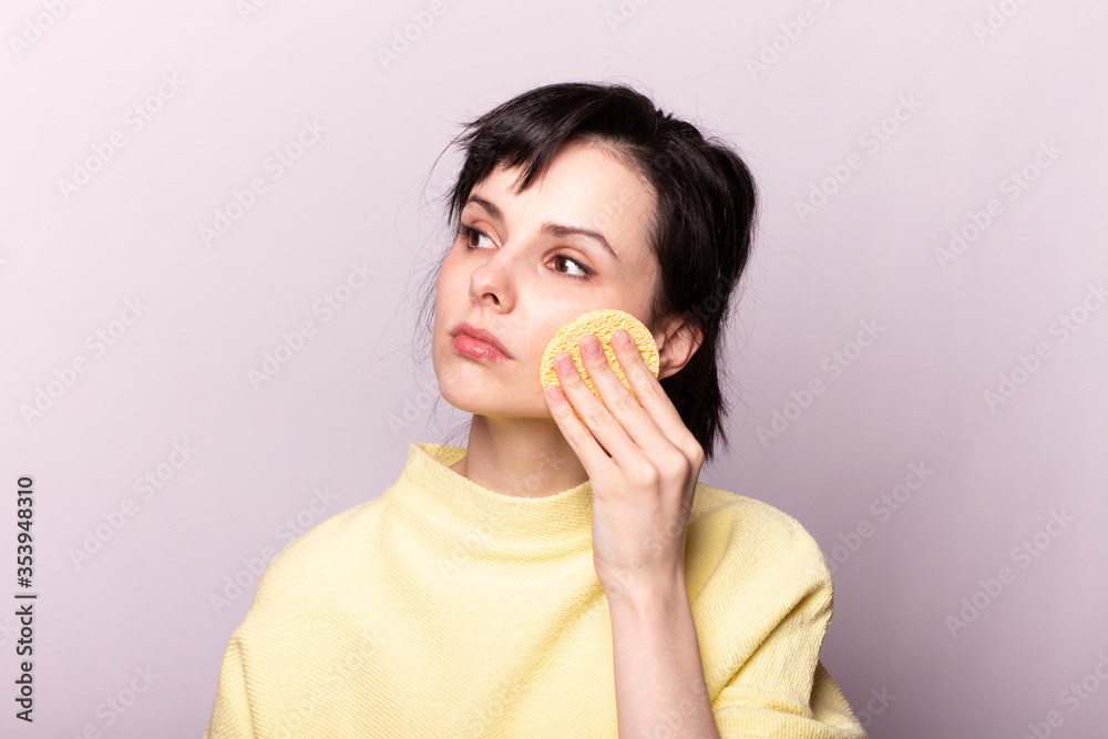 beautiful girl in a yellow sweater holds a sponge in her hands beautiful girl in a yellow sweater holds a sponge in her hands