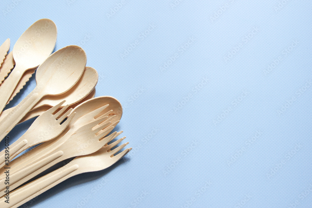 Eco-friendly tableware. Spoons, forks, knives made of wood. Tableware is on the left side Eco-friendly tableware. Spoons, forks, knives made of wood. Tableware is on the left side