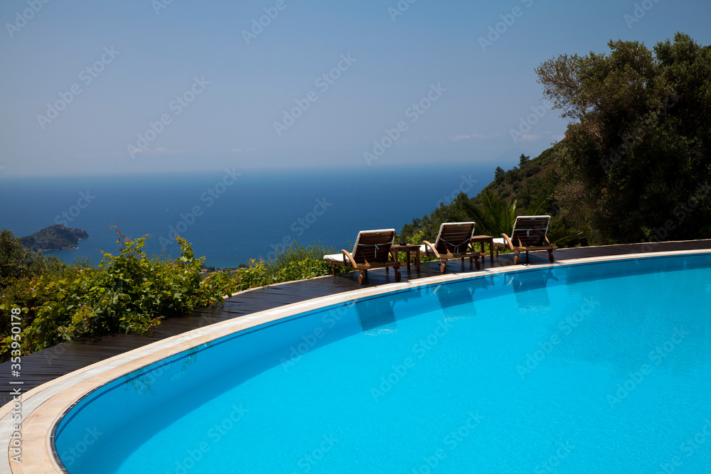 Swimming pool in the garden and beautiful sea and mountain landscape with trees.