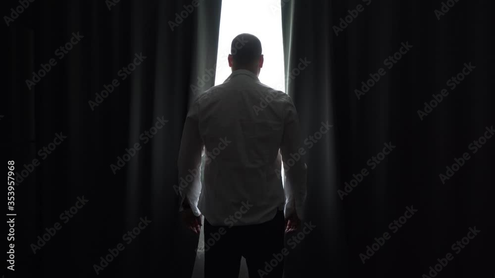 Businessman in the morning at home, in unbuttoned shirt opens curtains and looks in window. Curtains swing open with the help of young bald guy. Businessman in the morning at home, in unbuttoned shirt opens curtains and looks in window. Curtains swing open with the help of young bald guy.