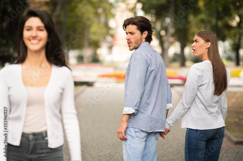 Boyfriend Looking At Other Girl Walking With Irritated Girlfriend Outdoor