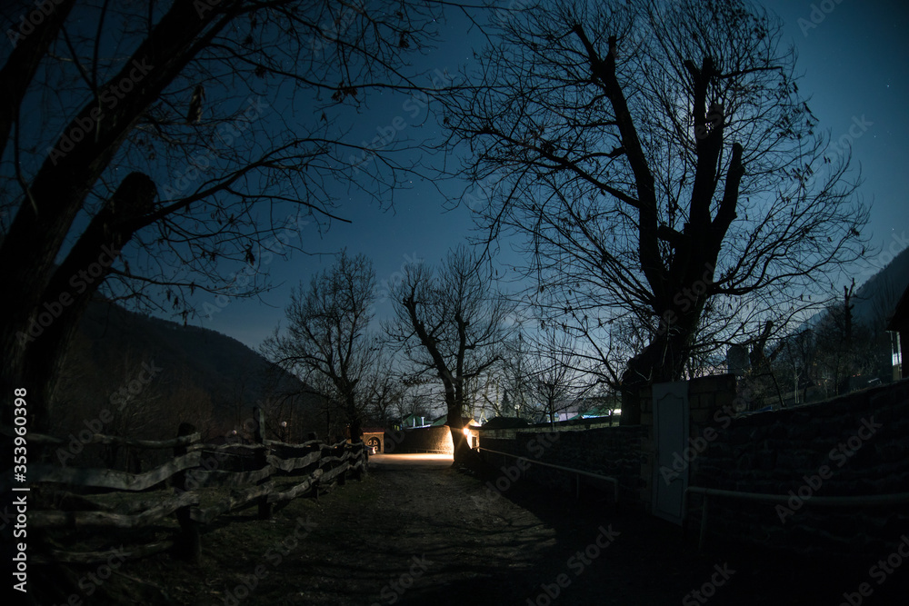 Fototapeta premium Full moon over quiet village at night. Beautiful night landscape of old town street with lights
