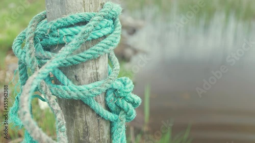 weathered green Rope tying up lake boat to wooden post photo