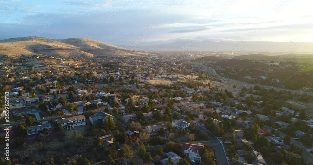 High altitude fly over retirement community in small Northern Arizona town with rich warm colors, spectacular background hills and distant clouds at sunrise.