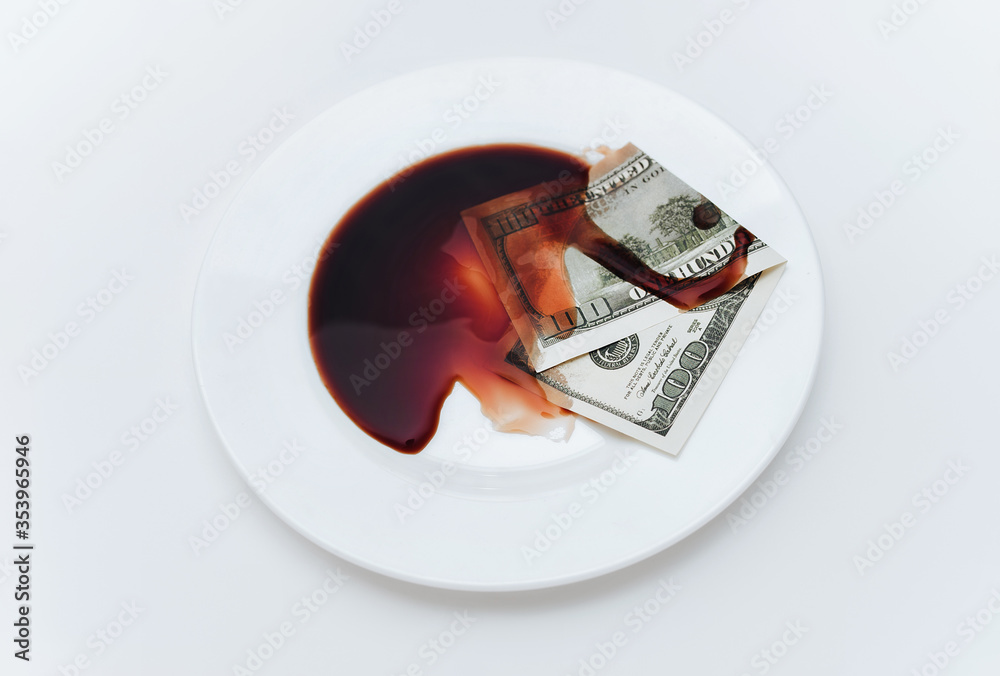A hundred-dollar bill lies in a white plate next to blood-like soy sauce on tablecloth. The concept of contracted political assassination, killer work, and death-related businesses. A hundred-dollar bill lies in a white plate next to blood-like soy sauce on tablecloth. The concept of contracted political assassination, killer work, and death-related businesses.