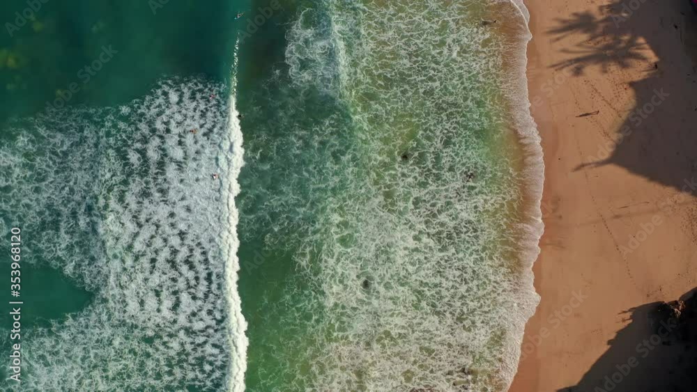 Aerial top view of ocean blue waves break on a beach. Sea waves and beautiful sand beach aerial view drone shot. Bird's eye view of ocean waves crashing against an empty sand beach from above. Aerial top view of ocean blue waves break on a beach. Sea waves and beautiful sand beach aerial view drone shot. Bird's eye view of ocean waves crashing against an empty sand beach from above.