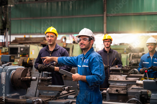 Professional technicians and engineers group wearing protective clothing are working in the industrial plants. Hold the tablet in your hand to see how the machine works. © Thirawatana