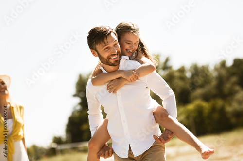 Happy Father Carrying Daughter Going On Family Picnic In Countryside