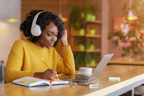Smiling black girl with headset studying online, using laptop photo
