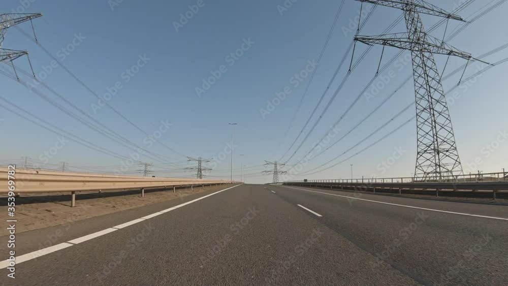 POV slow motion shot of a car driving on a highway surrounded by industry.