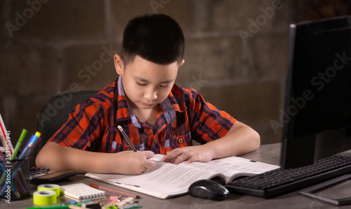 Asian boy student doing homework at home. Online Education and learning for kids concept.