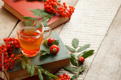 Autumn, fall leaves, cup of tea, opened book on wooden table. Seasonal, book reading, Sunday relaxing, teatime and still life concept. Selective focus, copy sapace, warming beverage photo