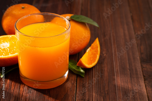 Fresh orange juice in glass and oranges fruit on wooden table background with copy space.