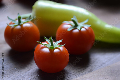 Fresh cherry tomatoes and banana peppers in ambient light.