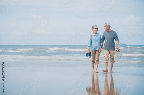 Romantic senior couple while walking hand in hands and talking together at beach..Retirement age concept and love, copy space for text