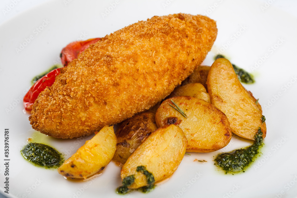 Chicken Kiev with potatoes and pesto sauce on a white plate