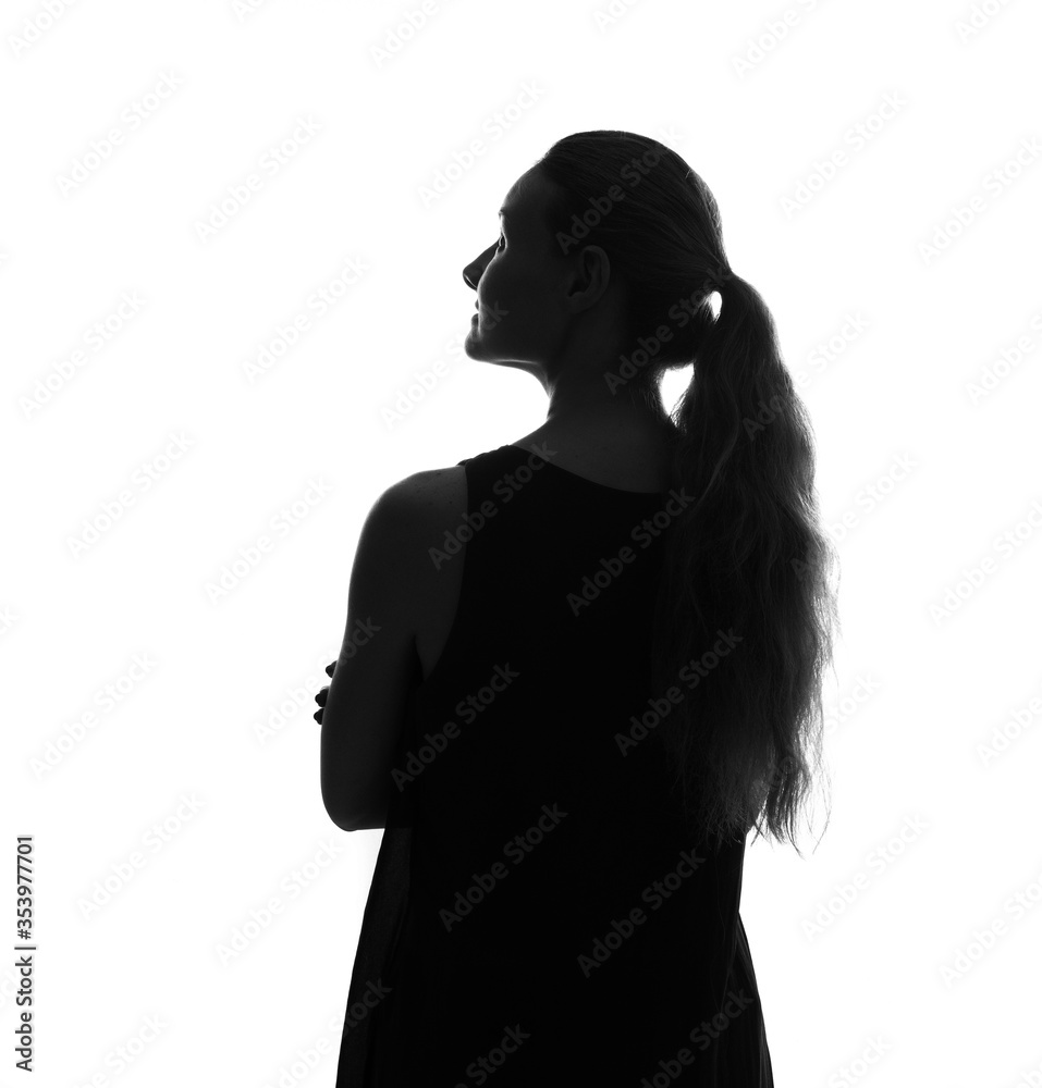 Female person silhouette from behind in the shadow, back lit light