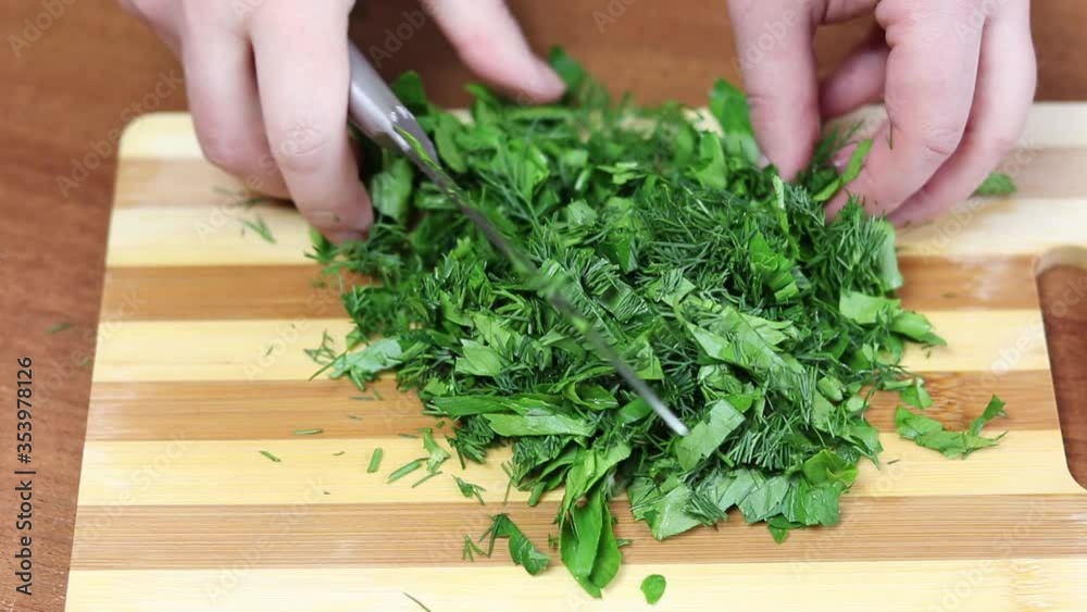 chop dill and parsley on a board with a knife chop dill and parsley on a board with a knife