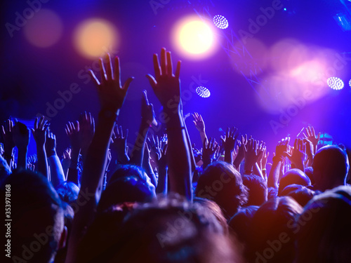 A crowd of people on the dancefloor with hands raised and disco lights, enjoying the music, dj, party, club, concert, crowd, people, music, band, performance