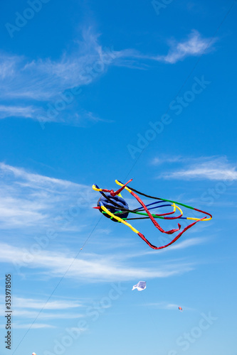 Long tailed red, black, blue & yellow kite flying above depok Beach at the Jogja air show in yogyakarta, Indonesia