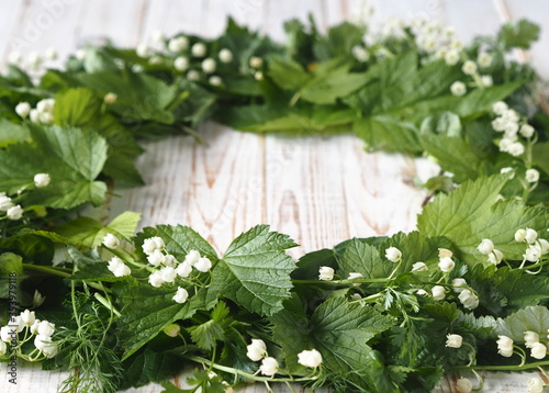 Spring collection of medicinal herbs.A wreath of Lily of the valley flowers with other medicinal plants on a wooden white table.