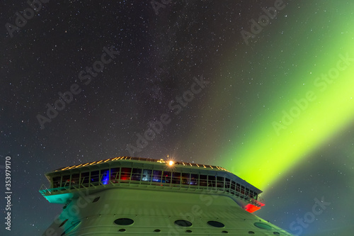 Aurora's ray of green light piercing night sky behind a cruise ship's bridge in Alaska. Starry sky as a background.