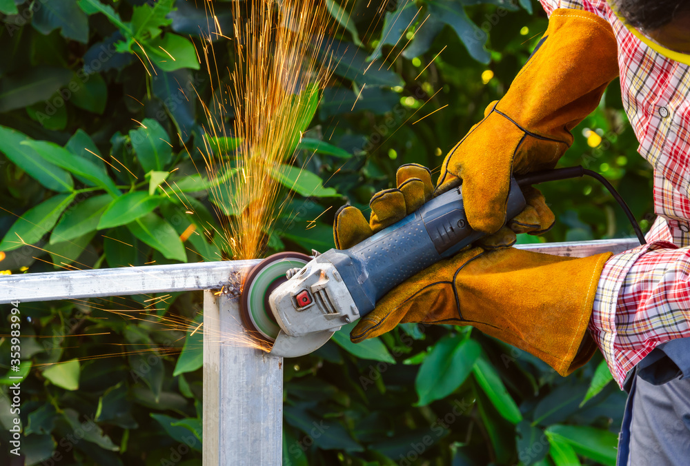 Worker grinding steel frame with handheld angle grinder. Grinding with sparks flying. Worker grinding steel frame with handheld angle grinder. Grinding with sparks flying.