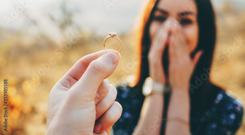 Bilde på lerret Close up photo of a wedding ring with diamond shown to the girl while she is ama