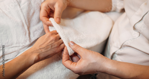 Caucasian masseur drying the client's hand after massage with a spa glove