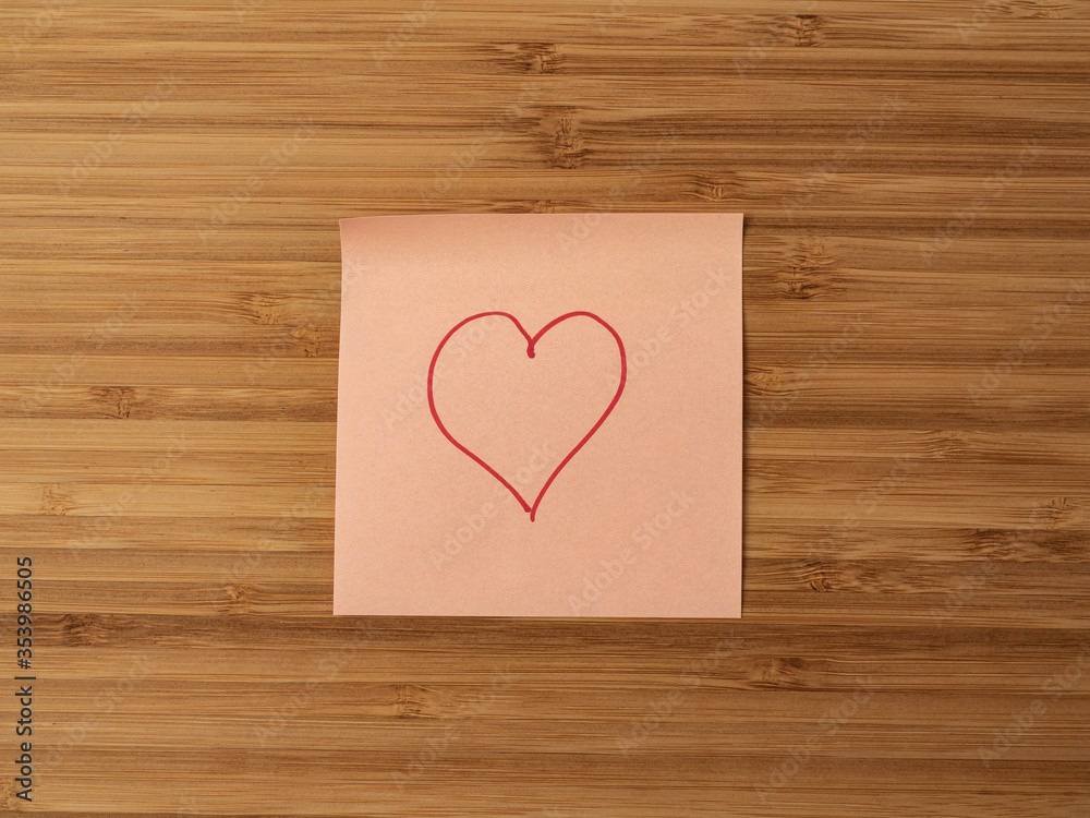 A paper sticker pasted on a wooden surface with the image of the heart symbol A paper sticker pasted on a wooden surface with the image of the heart symbol