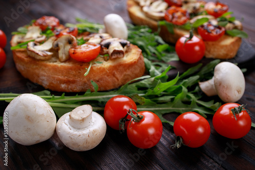 Tomato and mushroom bruschettas with arugula. Grilled snack, vegetarian toasts. Homemade italian appetizer