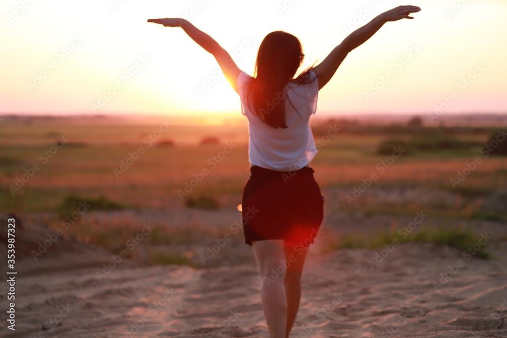 Obraz premium a girl alone in nature at sunset enjoys freedom and nature, happiness in the fresh air, psychological freedom and happiness
