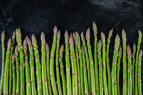 Background from the pods of green asparagus lying on a black background throughout the frame. Healthy eating