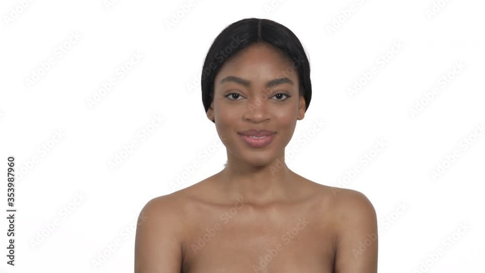 Flirting seductive African woman with naked shoulders covering lips with hand, smiling and posing at the camera. Isolated, on white background Flirting seductive African woman with naked shoulders covering lips with hand, smiling and posing at the camera. Isolated, on white background
