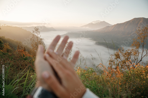 The couple of travelers holding hands at sunset in the mountains. Hands are blurred, focus on the mountains. Travel together concept