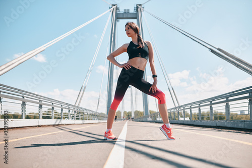 Sporty girl stretching outdoor on the bridge
