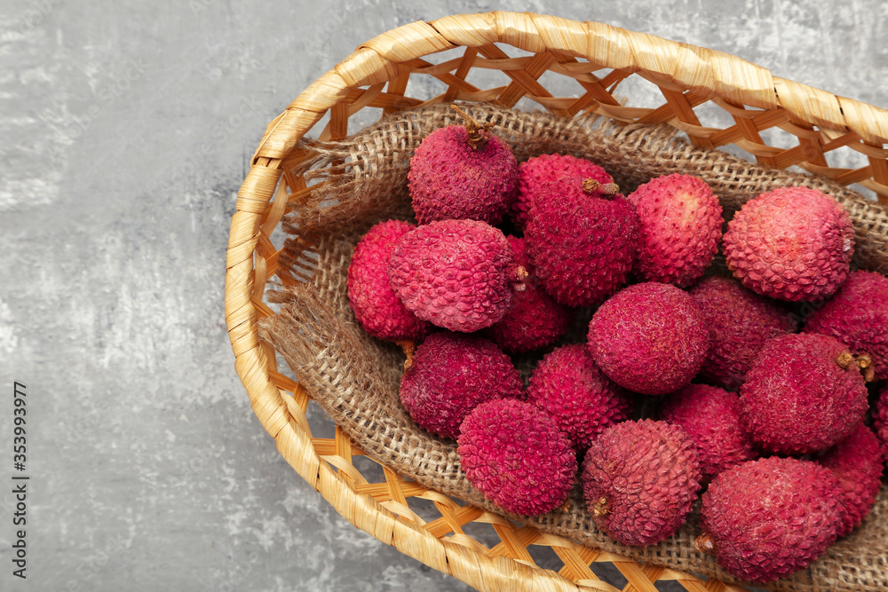 Tasty lychee in basket on grey background