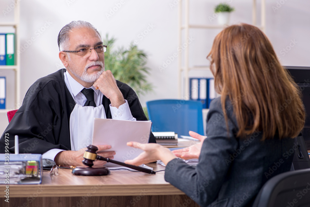 Old male judge and female client in the office Old male judge and female client in the office