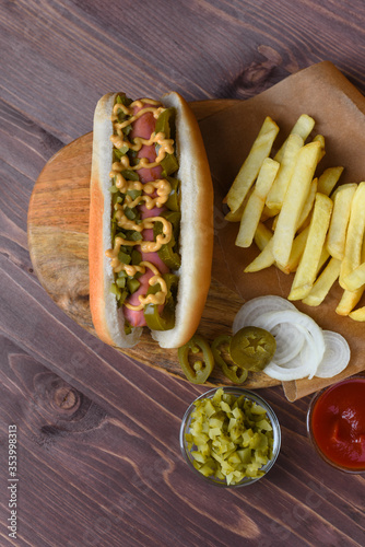 Homemade Hot Dog With Yellow Mustard, Onion, Pickles and French Fries. Ready-to-eat. Hotdog on rustic background.