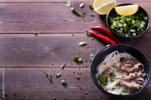 Asian cuisine, Vietnamese pho bo soup in a black plate on a wooden background