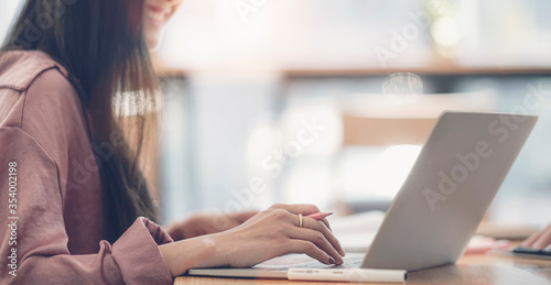 Cropped shot of young attractive asian woman working with laptop with happiness while sitting in co-workspace.
